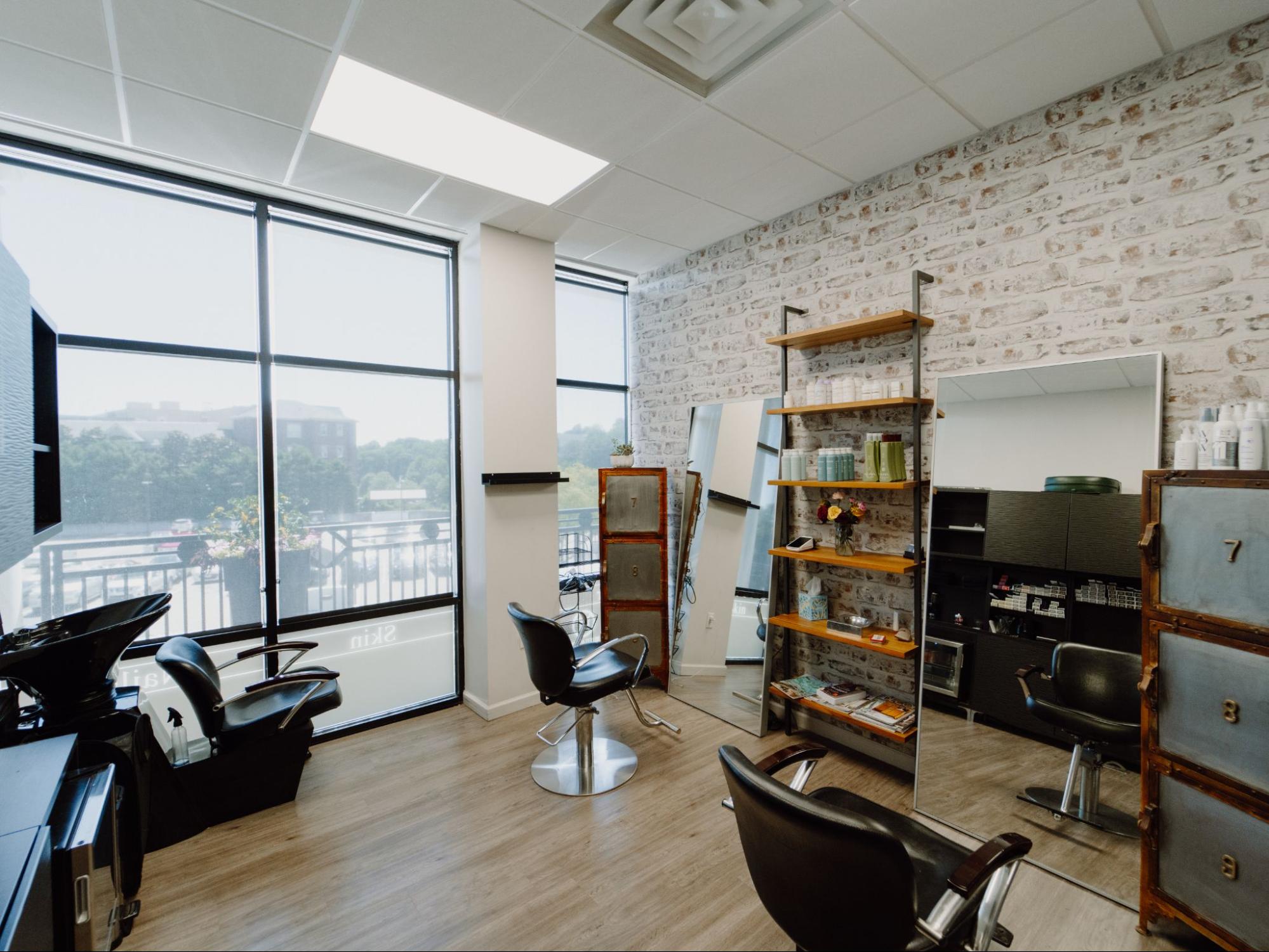 Lease a salon studio featuring styling stations, shampoo area,
  product display, brick wall, and floor-to-ceiling windows.