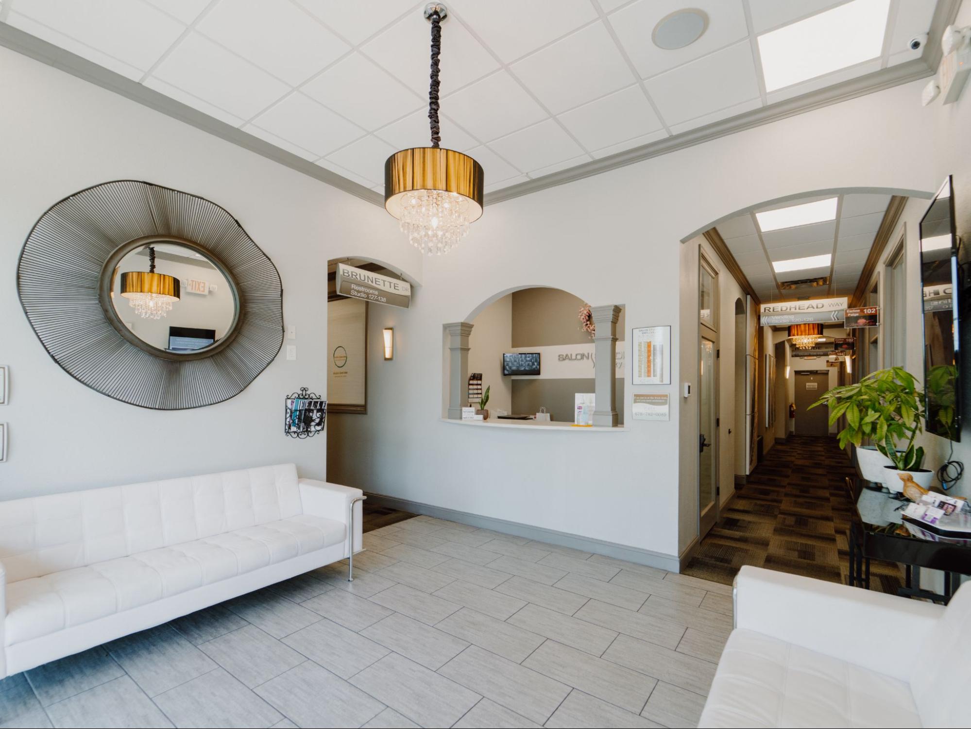 Premium Salon Studio for Lease - Stylish Reception and Lobby Space Professional salon studio for lease showing waiting lounge,
reception, chandelier, mirror, and hallway entrance.